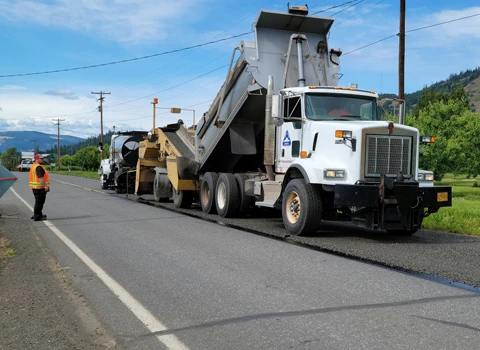 Construction equipment semi laying down gravel on road