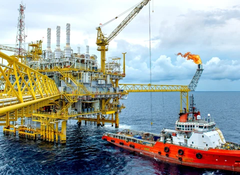 Oil and Gas rig on the ocean with boat pulling up to it